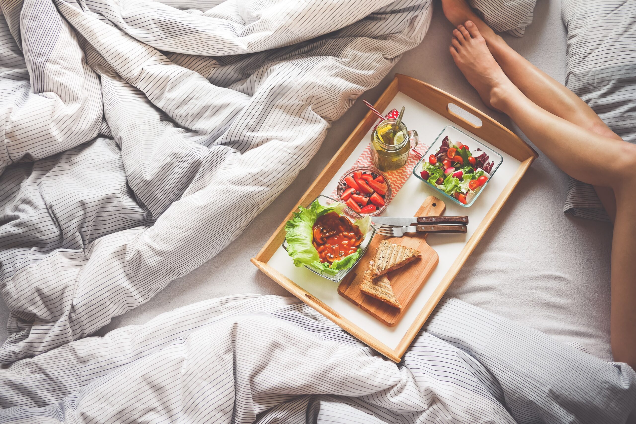 Bilden visar en frukostbricka och en person som tagit lite härlig sovmorgon i sängen. Brickor finns som liten bricka, stor bricka samt vackert designade frukostbrickor.