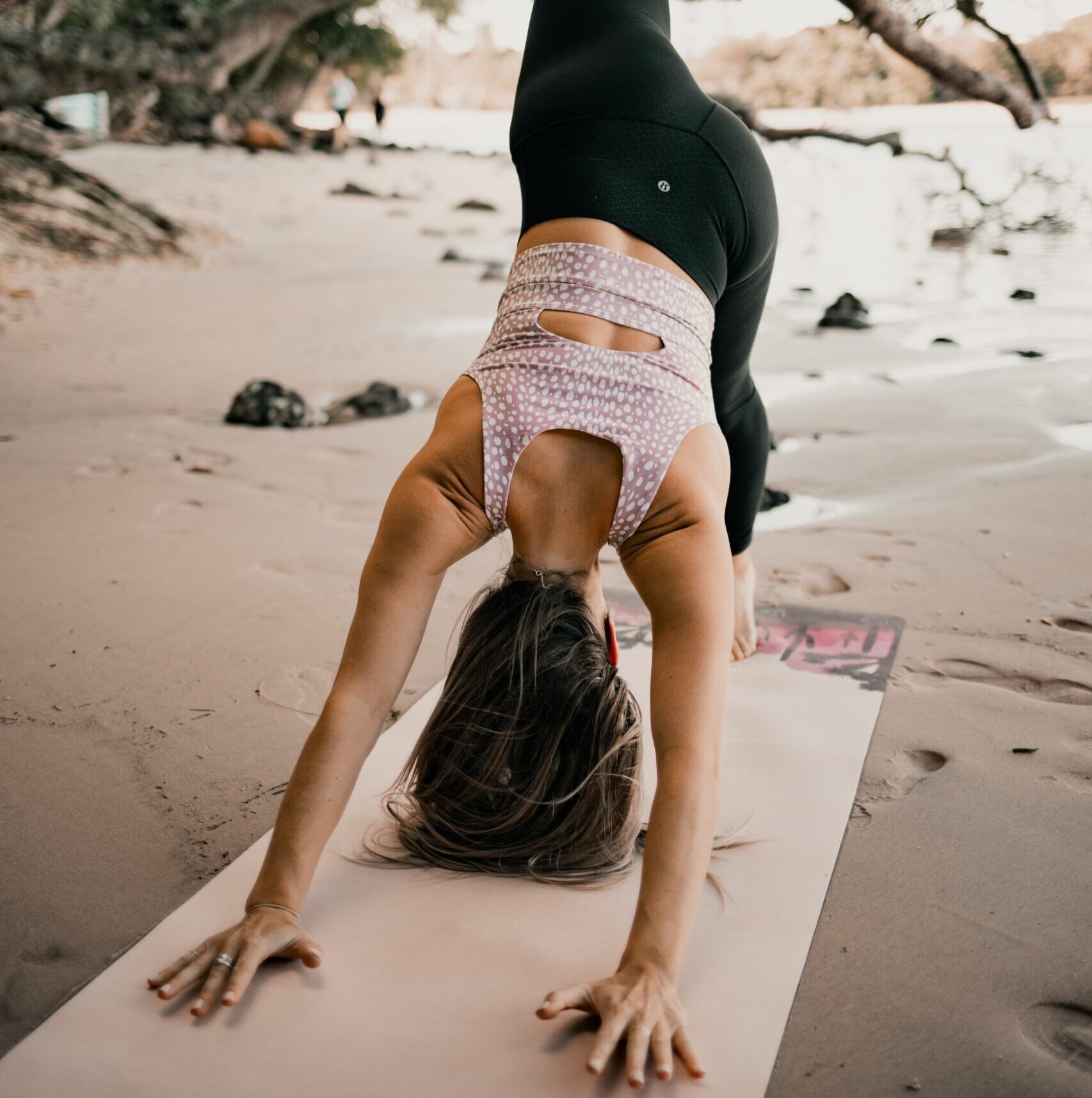 Bilden visar en person som utövar yoga på en strand i yoga tights med skön passform.